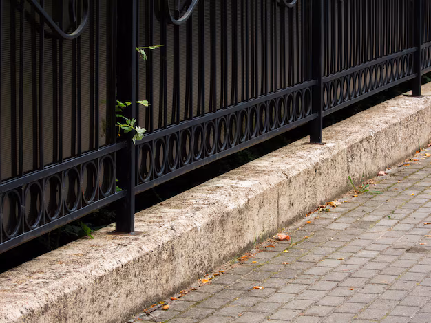 Decorative black metal fence along a sidewalk