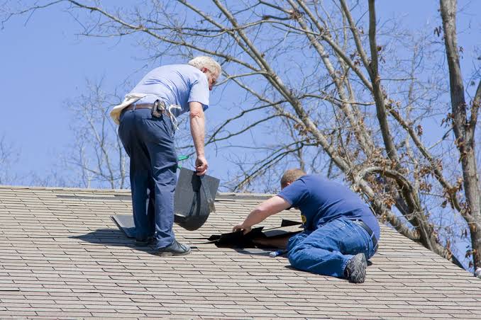 A roofing contractor and insurance adjuster reviewing hail damage on a roof together