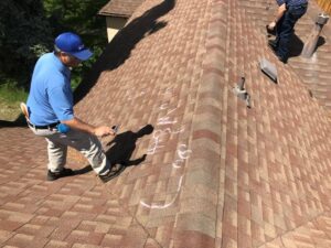 A local roofing contractor inspecting hail damage on a residential roof in Greeley, Colorado